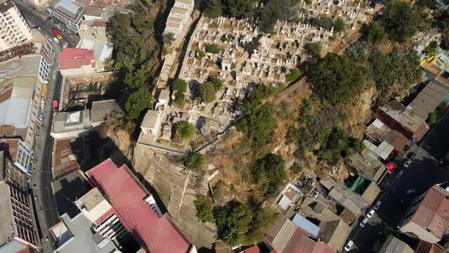 Aerial shot drone orbits to the left from high angle over cemetery on a hill