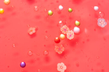 Colorful gel texture, clear skincare cream with bubbles and decorative figurines background, transparent beauty serum, colored cosmetic product close up