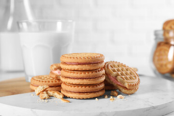 Tasty sandwich cookies with cream and milk on white board