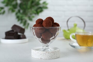 Dessert glass of delicious chocolate candies powdered with cocoa on white table