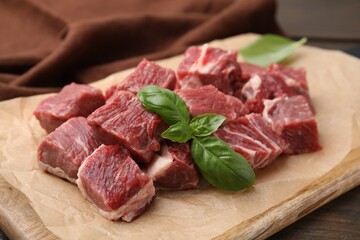 Cut fresh beef meat with basil leaves on wooden board, closeup