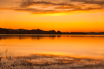 Fototapeta na wymiar Shades of orange sunrise waterscape