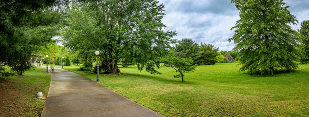 Path lined with exterior lights leading to a venue and surrounded by groomed lawn and trees