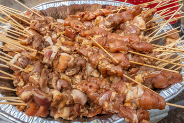 A large tray of filipino barbecue, marinated pork pushed onto skewers, ready to cook - obrazy, fototapety, plakaty