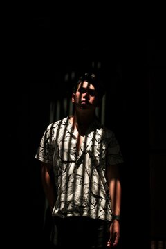 Man in white and black button up shirt sanding in between shadows