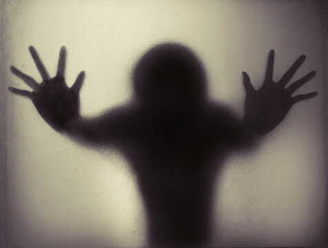 Silhouette of man leaning both hands on opaque surface