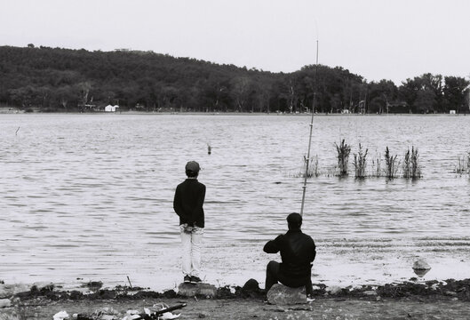 Two men fishing in lake in greyscale