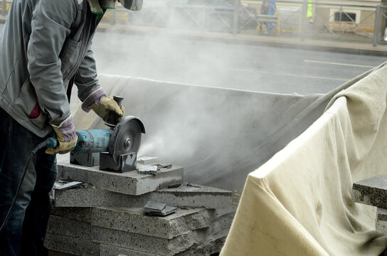 The worker cuts marble using angle grinder