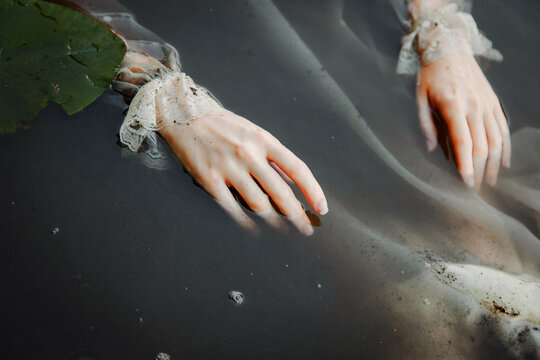 Woman hands floating in water next to green leaf