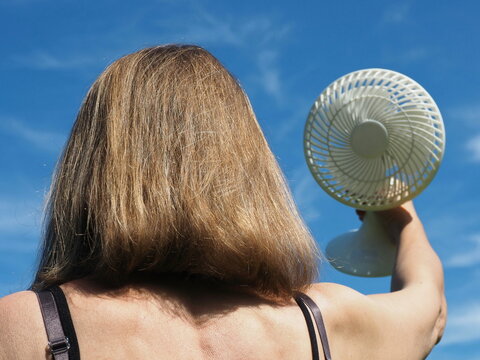 Woman in black tank top holding white fan