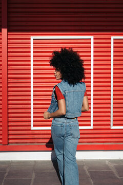 Woman in blue denim vest standing near red roll up door
