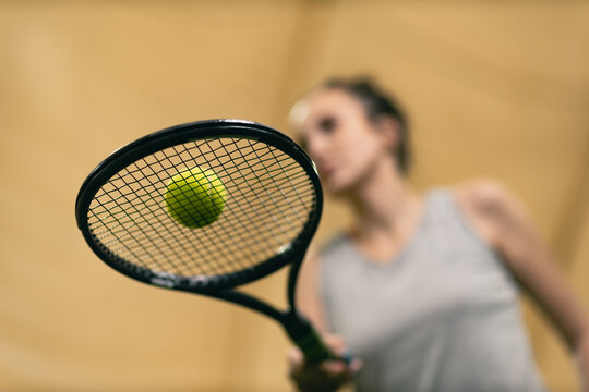 Woman in grey shirt holding tennis racket