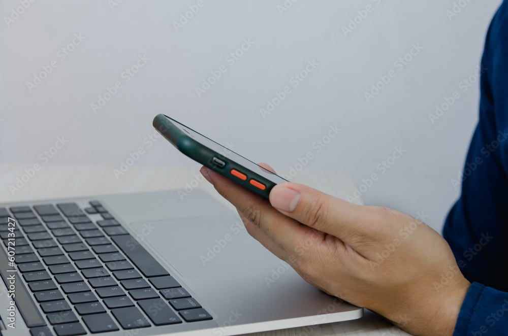 Aufkleber man holding mobile smartphone on table with computer laptop.