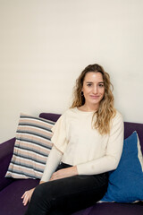 Woman smiling while sitting on a sofa at home.