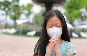 Young girl wear face mask with pray gesture for stop covid-19 during coronavirus outbreak.