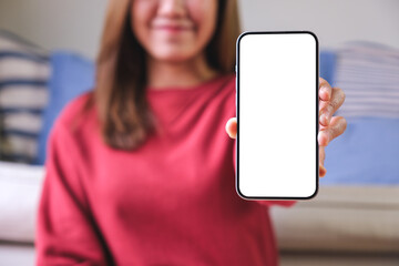 Mockup image of a young woman holding and showing a mobile phone with blank white screen