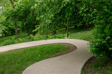 Winding walking concrete path in a summer park.