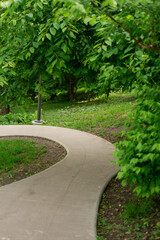 Obraz premium Winding walking concrete path in a summer park.