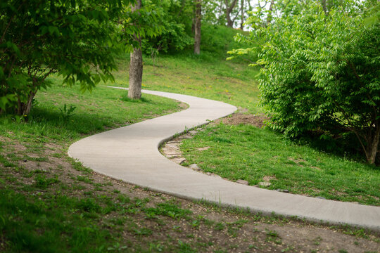 Winding walking concrete path in a summer park.