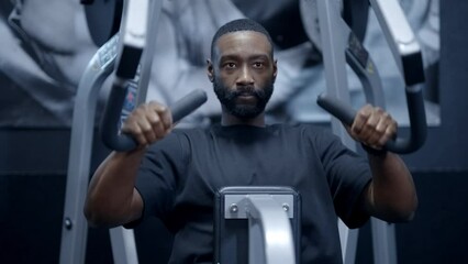 A focused African American man performing Lat Pull Downs in gym