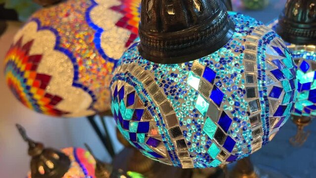 Bright multi-colored Turkish lamps hang in the store shine in different colors mosaic Colored stars and flowers painted on the lamps themselves
