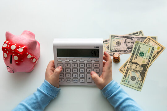 children's hands with calculator, money and piggy bank
