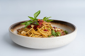 Spicy Thai basil pork pasta on white dish with white background. Italian food fusion Thai food. Tasty appetizing Italian fusion spicy spaghetti pasta with meat, chili, Thai basil. Italian fusion food.