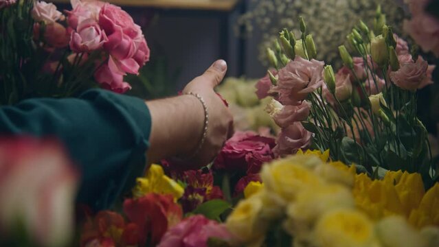 Close up shot of male professional florist, seller taking fresh flowers from vase and collecting bouquet for customer in flower store. Concept of floristry, retail small business and entrepreneurship.