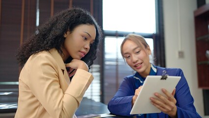 Asian women hotel receptionist in uniform giving hotel information service to women customer at hotel counters. Travel vacation concept