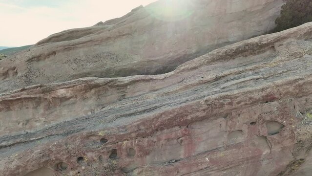 Aerial shot of the detailed and layered otherworldly terrain of Vazquez Rocks with the sun eventually peaking out from behind the rocks showing the unique structures often used for filming.