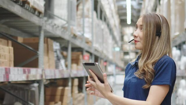 Asian female using tablet checking amount of stock product inventory on shelf at distribution warehouse factory. logistic business shipping and delivery logistic service.