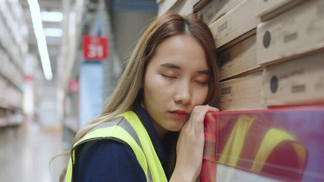 Asian female supervisors feel fatigue, exhaustion, headaches, sleepiness, and stress from heavy workloads in warehouse factory. 