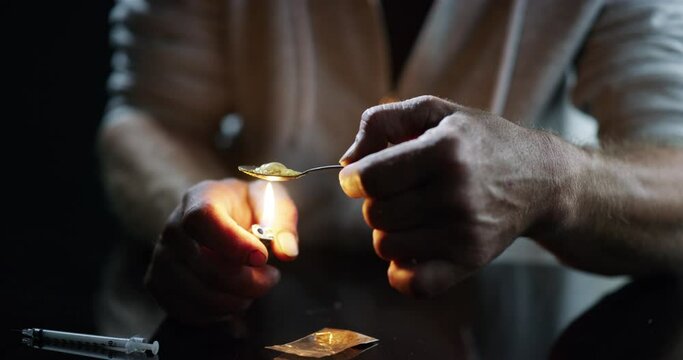 Drugs, addiction and man with lighter and spoon in studio isolated on black background. Drug addict, teaspoon and person with fire junkie cooking heroin chemical, crack problem and cocaine for crime