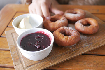 hand pick chocolate donuts with cream ad jelly on table 