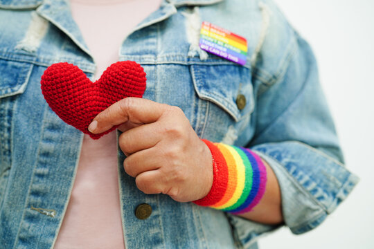 Asian woman holding red heart with rainbow flag, LGBT symbol rights and gender equality, LGBT Pride Month in June.