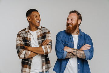 Two multinational male friends smiling and posing with arms folded