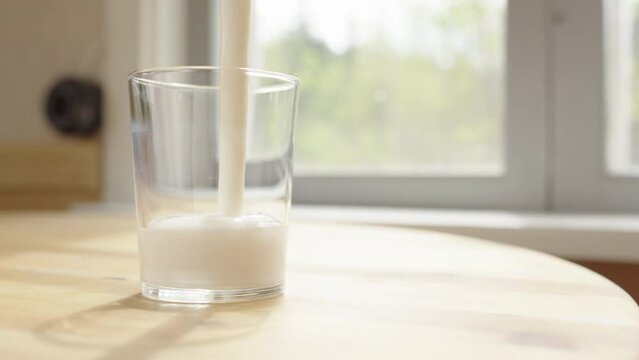 Fermented probiotic milk kefir poured into glass on table, close-up zoom in