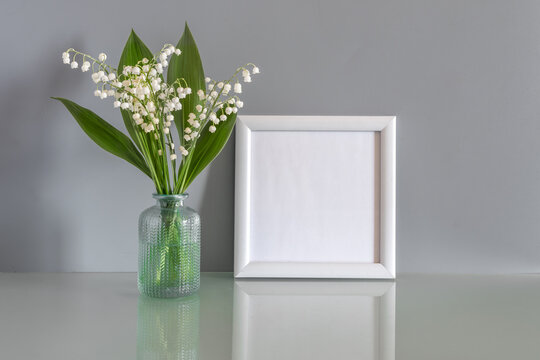 White wooden photo frame and a bouquet of flowers on a gray background