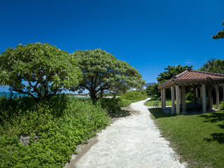 晴れた日の沖縄県読谷村の宇座海岸のビーチ沿いの遊歩道と赤瓦の東屋