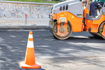 Road construction roller in motion rams fresh asphalt on the roadway. - obrazy, fototapety, plakaty