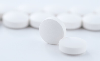 Close-up shot of a round pill against the background of tablets stacked in a row on a production line. Pharmacy medicine pill in production line at medical factory.