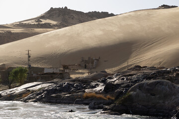 Piccole costruzione, rovine di case, sommerse dalla duna di sabbia lungo le rive del Nilo in Egitto