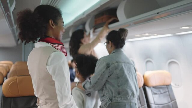 Women stewardess greeting passengers on airplane and checking passenger's boarding pass welcoming to the flight. Airline transportation