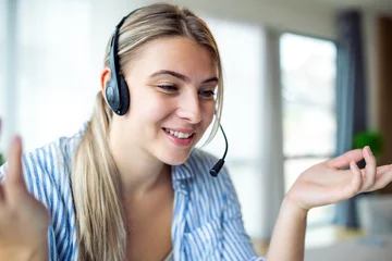 Foto op Plexiglas Young friendly operator woman agent with headsets. Beautiful business woman wearing microphone headset working in the office as a telemarketing customer service agent, call center job concept. © Graphicroyalty