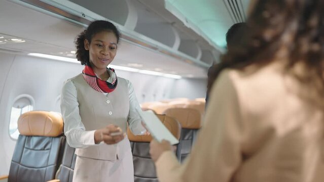 Women stewardess greeting passengers on airplane and checking passenger's boarding pass welcoming to the flight. Airline transportation