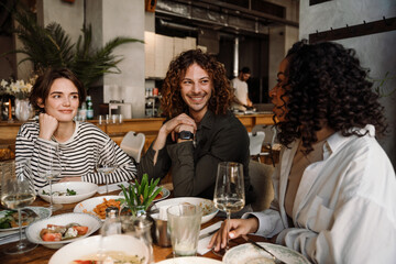Group of jotful friends talking while dining in restaurant
