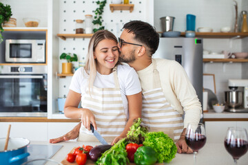 Portrait of happy young couple cooking together in the kitchen at home. romantic Attractive young woman and handsome man are enjoying spending time together while standing on light modern kitchen.