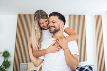 Portrait of young couple sitting on bed and look at each other. Attractive beautiful new marriage man and woman in pajamas enjoy morning activity in bedroom at home. Family relationship concept.