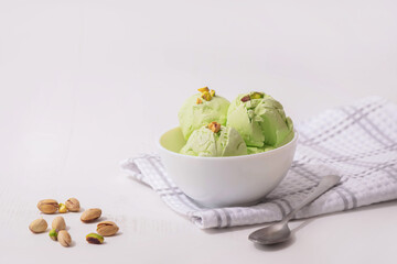 Pistachio homemade Ice cream in a white bowl on a white kitchen table, copy space. Summer cooling desserts