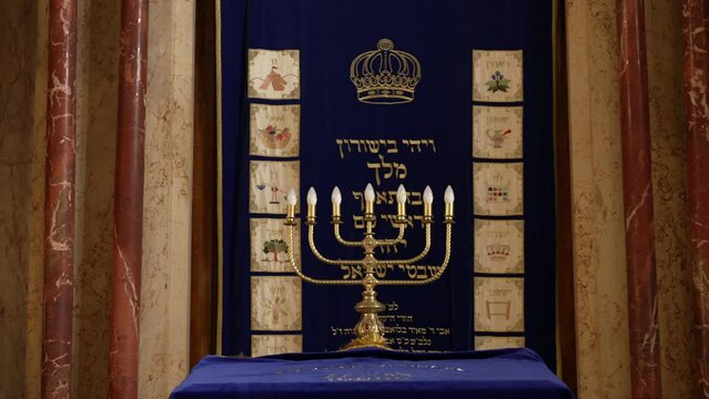 Jewish menorah candelabra displayed in museum with Hebrew text in background